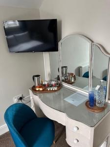 een bureau met een blauwe stoel en een spiegel bij Most Easterly Guest House in Pakefield