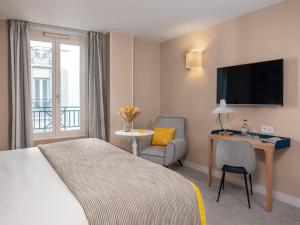 パリにあるホテル ル マレイユのベッド、椅子、テレビが備わるホテルルームです。