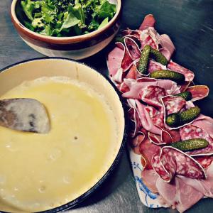 a table with a plate of meat and a bowl of salad at Hôtel Restaurant "La Petite Auberge" in Bourg-Saint-Maurice