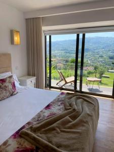 a bedroom with a bed and a large window at Vale da Fonte - Charming Houses in Ponte da Barca