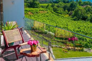 d'un balcon avec des chaises et un vase de fleurs roses. dans l'établissement Vale da Fonte - Charming Houses, à Ponte da Barca