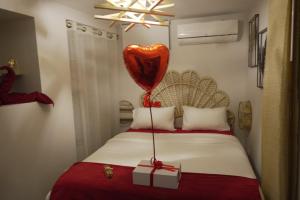 - un ballon à cœur rouge et un cadeau sur un lit dans l'établissement T2 Jacuzzi Disneyland Paris Résidence Belle Créole, à Quincy-Voisins