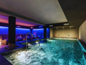 a pool in a hotel room with blue lighting at Hotel Orso Grigio in Pescul