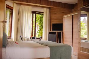 a bedroom with a bed and a table and a television at Pousada da Torre in Morro de São Paulo