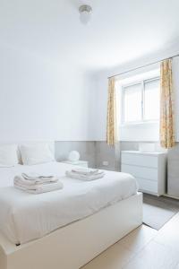 ein weißes Schlafzimmer mit einem weißen Bett und einem Fenster in der Unterkunft Lisboa - Moscavide, Parque das Nações Apartment in Lissabon