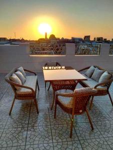 a table and chairs on a roof with the sunset at Hotel Times in Bukhara