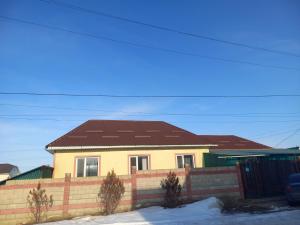 ein gelbes Haus mit braunem Dach in der Unterkunft Askar Guesthouse in Karakol