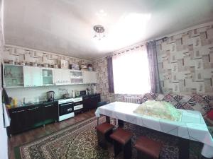 a living room with a table and a kitchen at Askar Guesthouse in Karakol