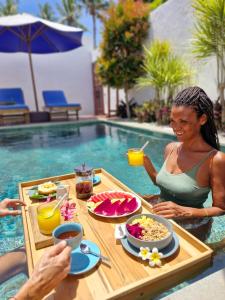 eine Frau, die an einem Tisch vor einem Pool sitzt in der Unterkunft The Sanctuary -Private pool villas in Gili Air