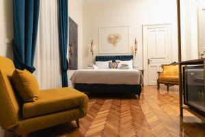 a bedroom with a bed and a chair and a television at Villa Clio, a Luxury Collection in Thessaloniki