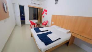 阿里巴格的住宿－Samara Sea View Resort，一间卧室配有一张带红色椅子的床和一张桌子