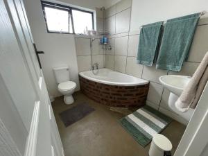 a bathroom with a tub and a toilet and a sink at The Stables, Central Garden Cottage in Howick in Howick