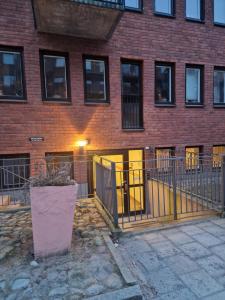 a brick building with yellow doors and a fence at Nomad Gardet in Stockholm