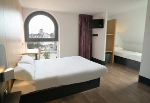 a bedroom with a white bed and a window at B&B HOTEL Dreux Centre in Dreux