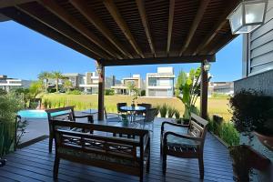 eine Holzterrasse mit Stühlen, einem Tisch und einem Pool in der Unterkunft Casa 4 Suítes com piscina Fundos Lago-Ilhas Resort in Capão da Canoa