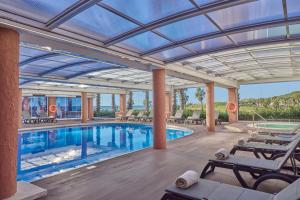 una piscina con sillas y un techo grande en Sunway Playa Golf & Spa Sitges en Sitges