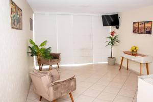 a living room with two chairs and a tv at Orla de Araruama in Araruama