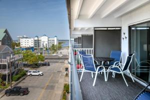 Un balcón con sillas azules, una mesa y una calle. en Ocean City Beach Retreat with Linens Included en Ocean City