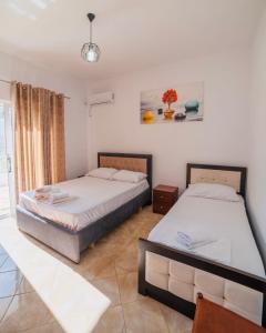 a bedroom with two beds and a window at Vila Feimi in Ksamil