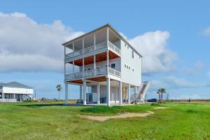a white building with balconies on a grass field at Sunset Bay in Galveston