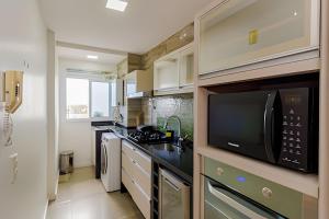uma cozinha com um micro-ondas e um lavatório em Apartamento Espaçoso & Aconchegante - 3 quartos em Porto Alegre