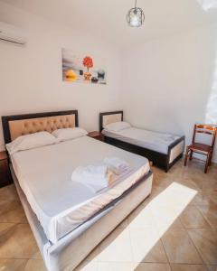 a bedroom with two beds and a chair at Vila Feimi in Ksamil
