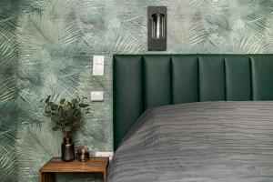 a bed with a green headboard next to a table at Luxury Tropical Apartment at Budapest in Budapest