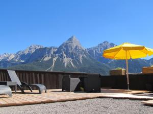 een terras met stoelen en een parasol en bergen bij Zugspitze 6,7 in Lermoos