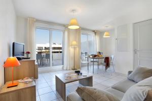 a living room with a couch and a tv at Vacancéole - Résidence Cap Camargue in Le Grau-du-Roi