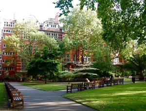 a park with benches in the grass and buildings at Mayfair Pied de Tier sleeps 6ppl in London