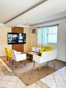 a living room with yellow and white chairs and a table at Hotel Lacala in Florianópolis