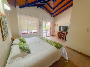 sypialnia z dużym białym łóżkiem z zielonymi poduszkami w obiekcie Hotel Barranqueros Soledén w mieście Armenia