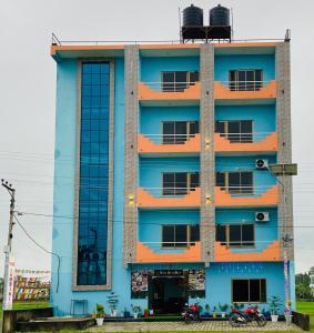 un bâtiment bleu avec des fenêtres et des motos garées devant dans l'établissement The Lumbini Hotel, à Rummindei