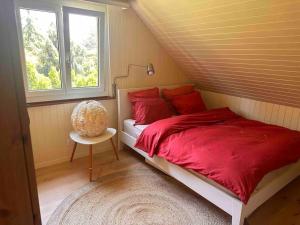 1 dormitorio con cama roja y ventana en Luxueuse oasis écologique à proximité du lac en Preverenges