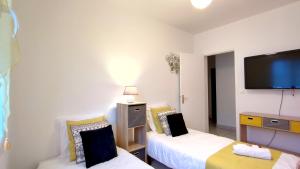 a room with two beds and a flat screen tv at Galets Blancs Yourhosthelper in Royan