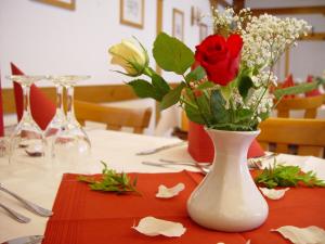 a white vase with red roses on a table at Gasthaus Debelius Beltershausen in Marburg an der Lahn