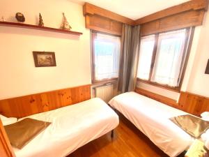 two beds in a room with two windows at FALORIA APARTMENT-splendid view in Cortina dʼAmpezzo