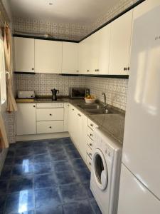 eine Küche mit weißen Schränken und einer Waschmaschine in der Unterkunft Apartamento frente al Mediterraneo in Torreblanca