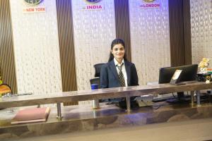 een vrouw zit aan een bureau vooraan bij Hotel Royal Inn igi in New Delhi