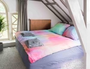 a bed with a colorful blanket on it in a room at Bohemian Experience Wellness, Jacuzzi, Sauna, BBQ, Garden, Sleeps 14 in Kockengen