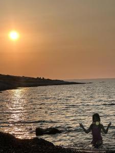 un niño sentado en el agua en la playa al atardecer en Villa Flora, Piscina Esclusiva e Mare, en Augusta