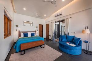 a bedroom with a bed and a blue couch at SaffronStays Mimosa Sunsets in Dapoli