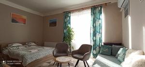 sypialnia z łóżkiem i dwoma krzesłami oraz oknem w obiekcie Karancs Apartman Salgótarján w mieście Salgótarján
