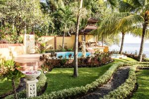 een tuin met een zwembad en palmbomen bij Teluk Indah Beach & Pool Villa in Tejakula