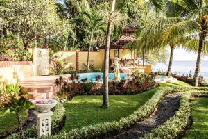 a garden with a swimming pool and palm trees at Teluk Indah Beach & Pool Villa in Tejakula