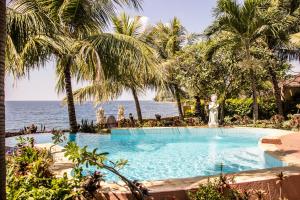 een zwembad naast de oceaan met palmbomen bij Teluk Indah Beach & Pool Villa in Tejakula