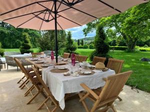 un lungo tavolo con sedie e ombrellone di Maison d'hôtes et gîte en Sarthe a Saint-Christophe-en-Champagne