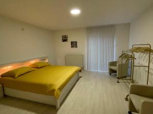 Un dormitorio con una gran cama amarilla y una silla en Vakantiewoning Villa 35, en Maasmechelen