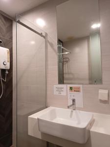a white sink in a bathroom with a shower at Kino Hotel in Shah Alam