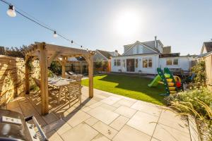 a backyard with a wooden pergola and a table at 4BR Beach House sleeps 10 - 5 mins walk to the Sea in West Wittering